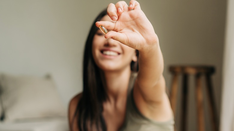 Woman smiling holding pill up