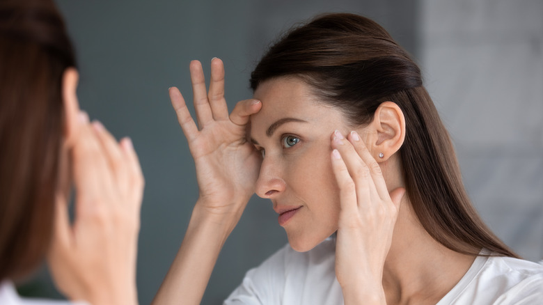 A woman inspecting her skin in the mirror 