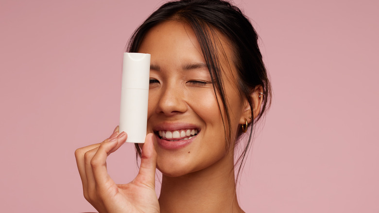 Smiling woman holding a cosmetic bottle