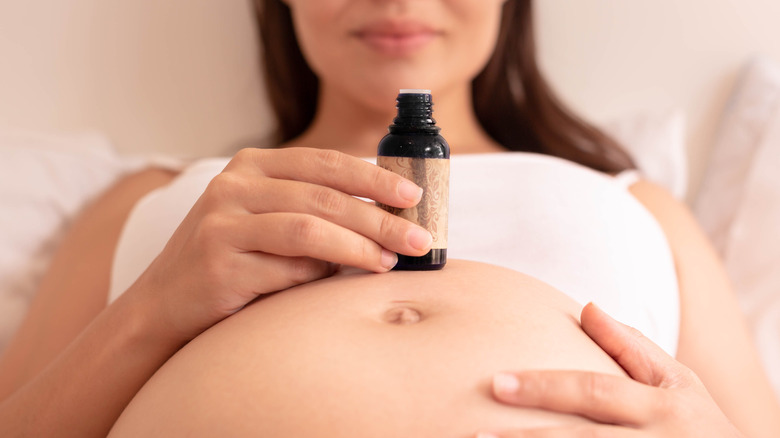 A pregnant woman holding a cosmetic bottle