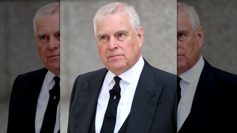 Prince Andrew, in dark suit and tie and white shirt, looking grim