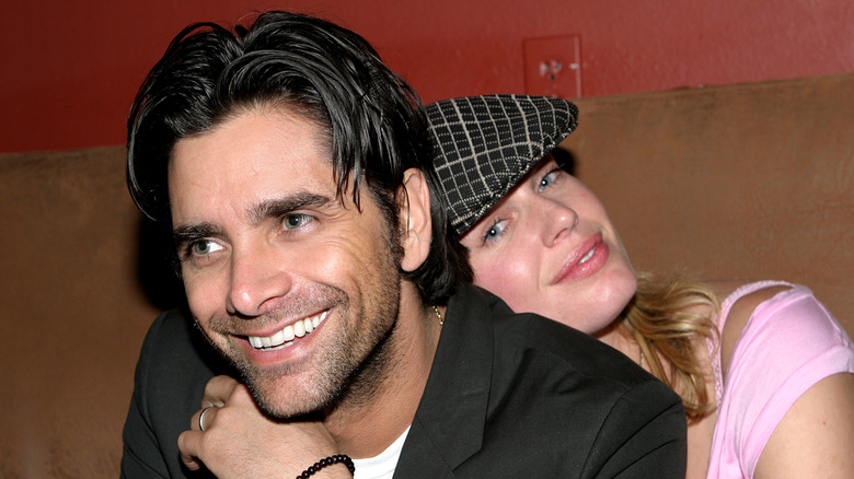 Rebecca Romijn and John Stamos holdng hands 