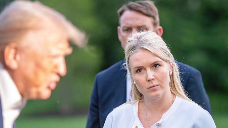 Karoline Leavitt listens to Donald Trump speak to reporters in May 2025