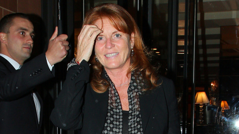 Sarah Ferguson walking with her hand over her head and smiling at the camera