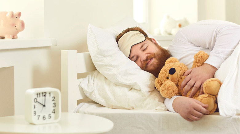 Happy man sleeps and cuddles his teddy bear