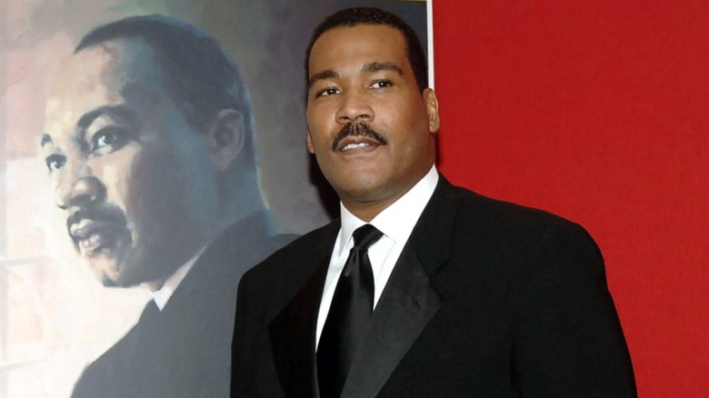 Dexter King posing alongside MLK Jr. portrait
