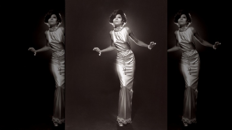 Diana ross in a slinky metallic high-necked dress with a graphic circular belt at the waist