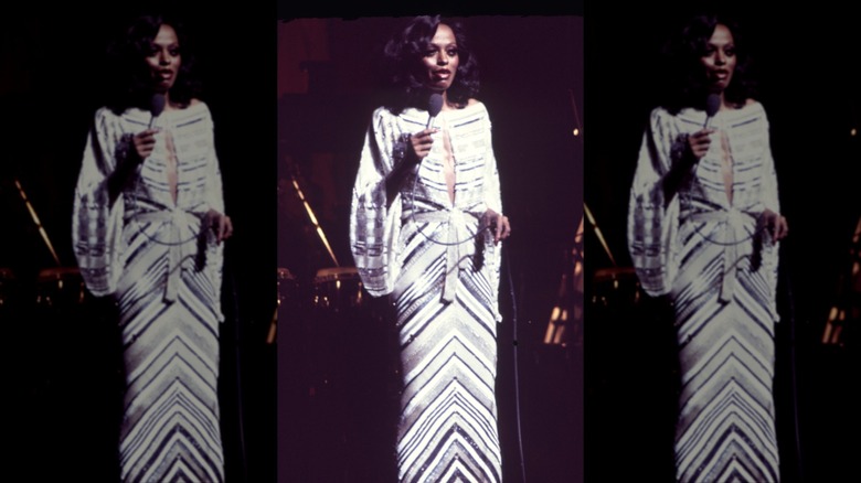 Diana Ross in a black and white striped floor length gown with a keyhole cut out along the center of her chest and long draping sleeves