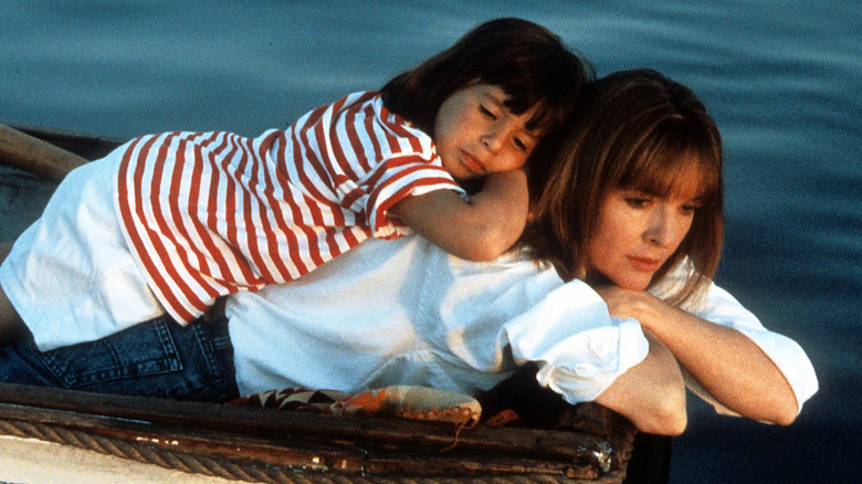Diane Keaton lying on her stomach above water with a child on her back.
