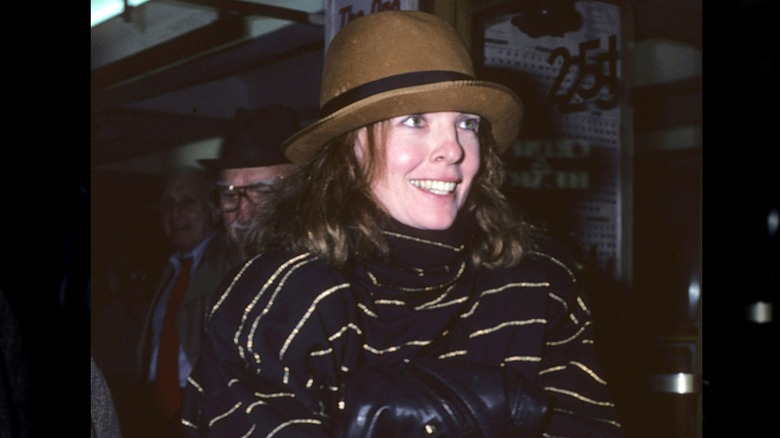 Diane Keaton in a brown hat, bundled up in the dark.