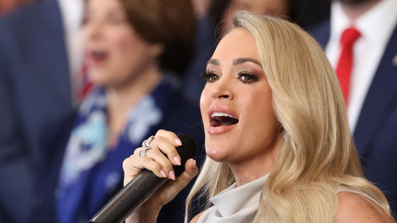 Carrie Underwood singing in a white dress