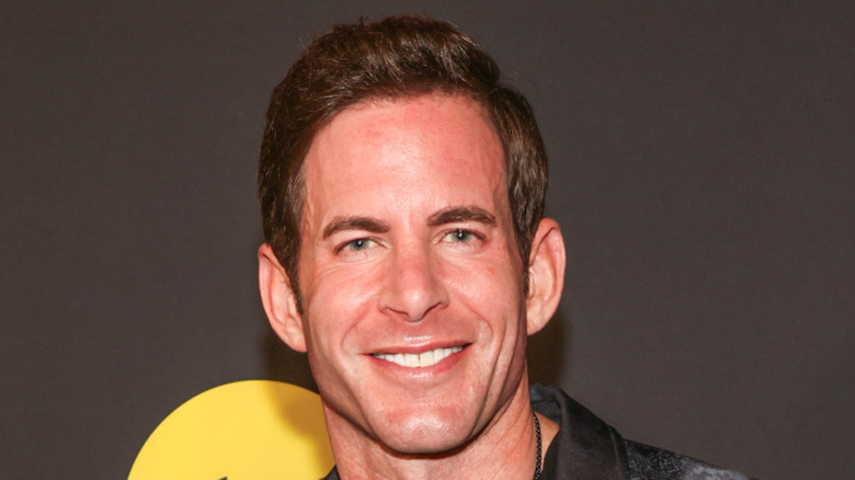 Tarek El Moussa smiling in a black shirt and black jacket.