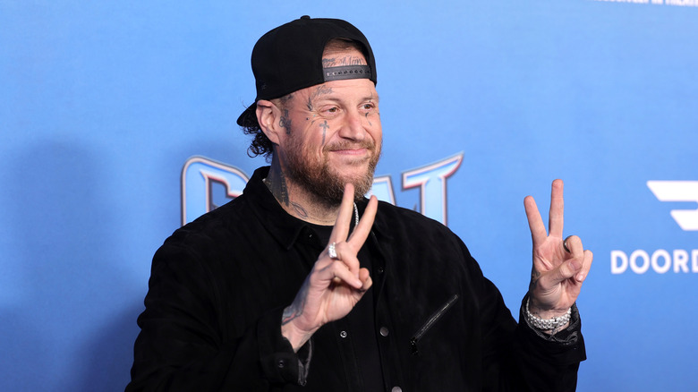 Jelly Roll holding up the peace sign with his hands at a red carpet event