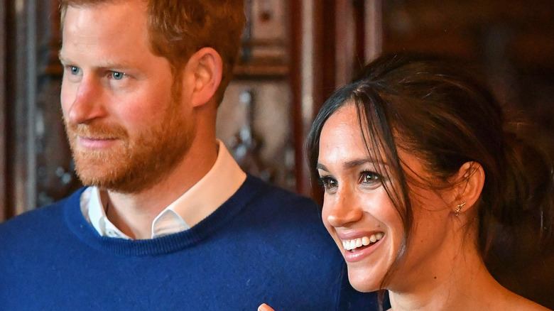 Prince Harry and Meghan Markle smile at an event.