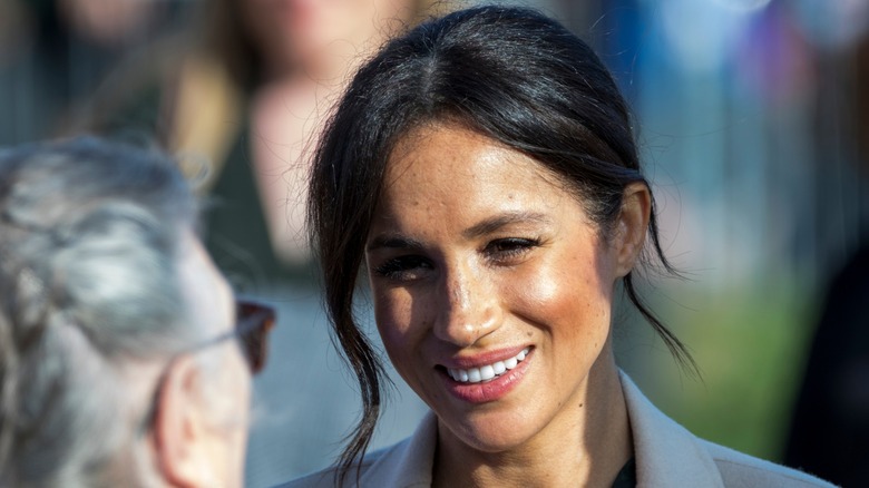 Meghan Markle smiling and talking with someone