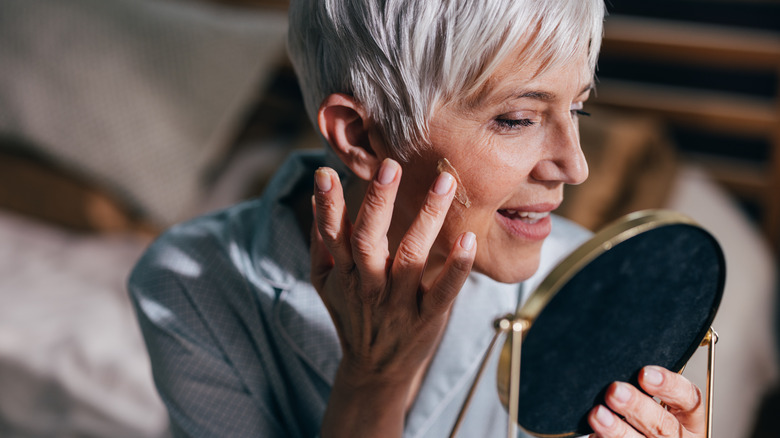 Mature woman applying makeup to cheeks