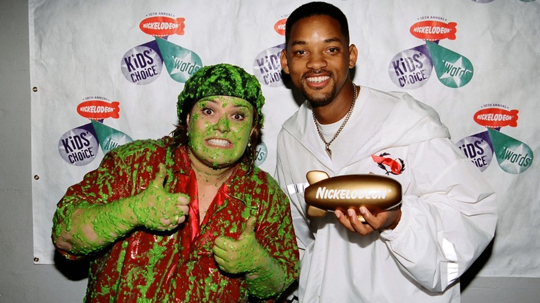 Rosie O'Donnell covered in green slime and giving two thumbs up next to a smiling Will Smith.