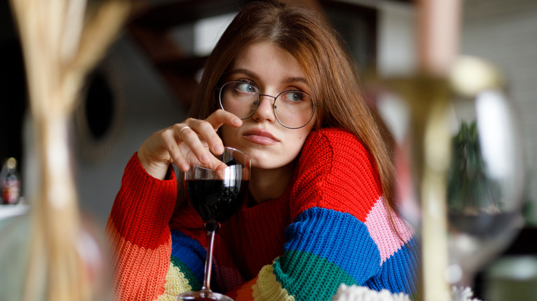 sad woman in glasses holding wine