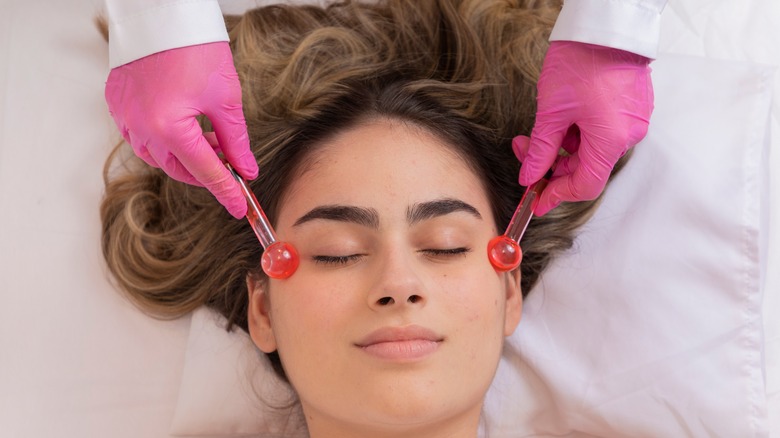 Woman getting facial globe massage