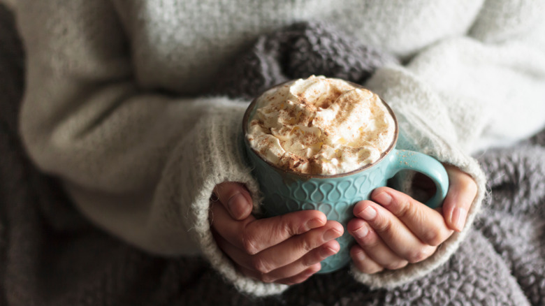 Woman sweater hands hold mug cocoa