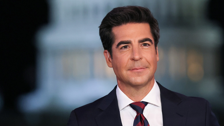 Jesse Watters posing in a suit with the Capitol building behind him