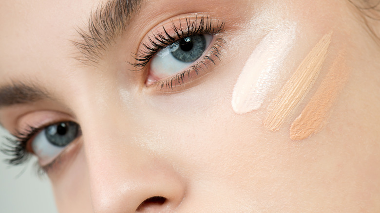 Woman with three swatches of concealer on under eyes 