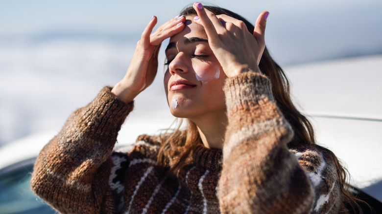 woman applying sunscreen to face