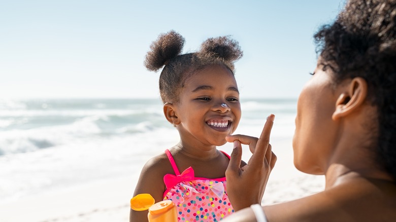 Woman applying sunscreen on child