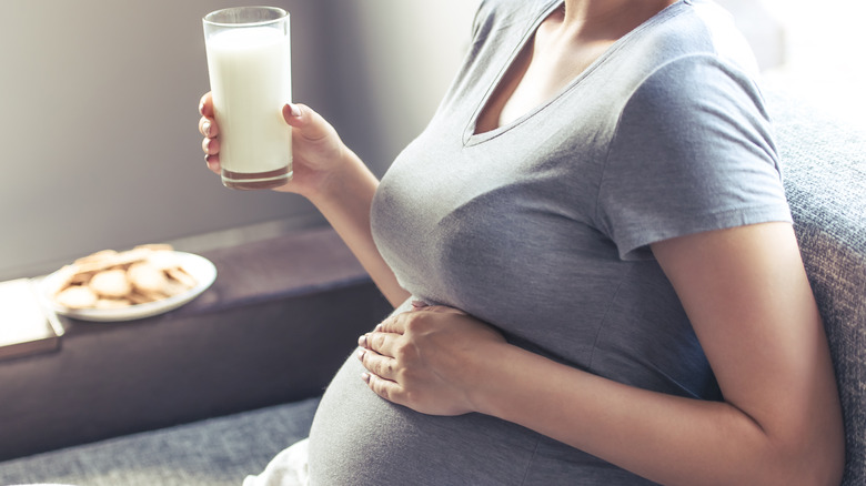 pregnant person holding glass of milk