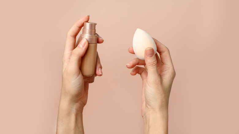 Holding a bottle of foundation and makeup brush
