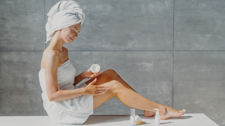 Woman applying lotion in bathroom