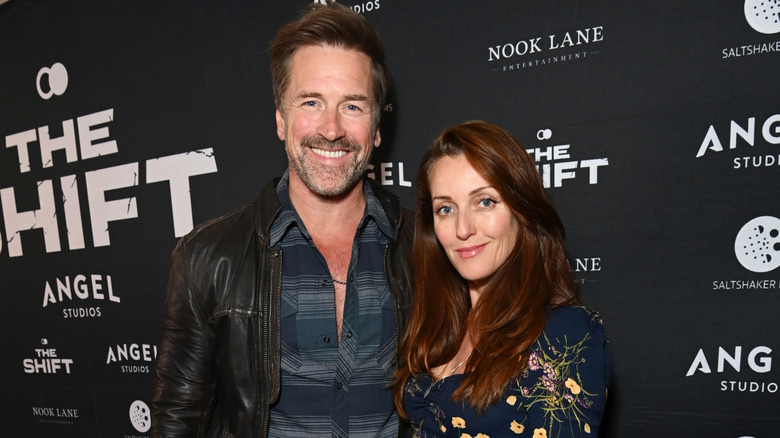 A smiling Paul Greene posing for photographs with Kate Austin at his side