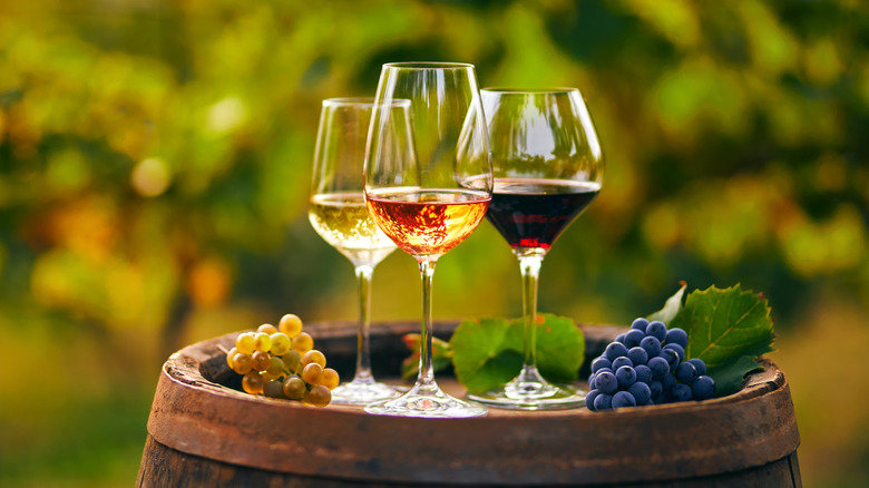 White and red wine glasses on a wine barrel grapes