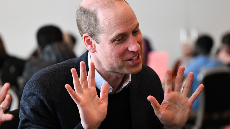 Prince William smiling with hands up