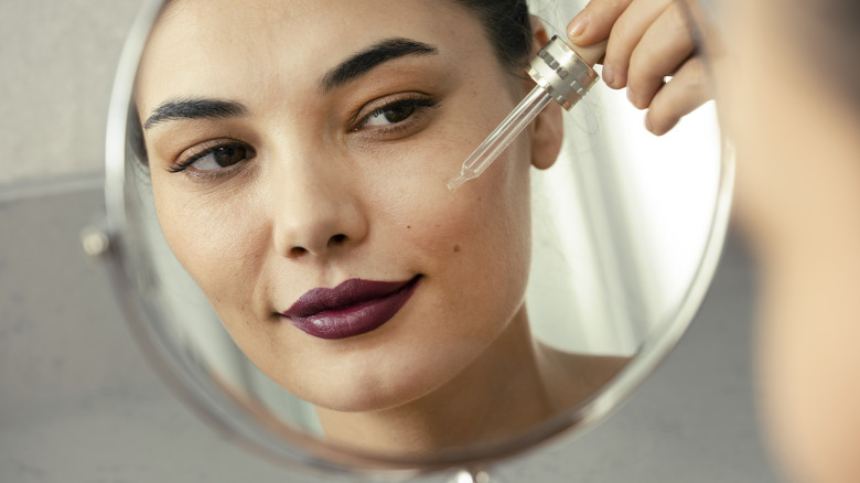 Woman applying retinol on face 