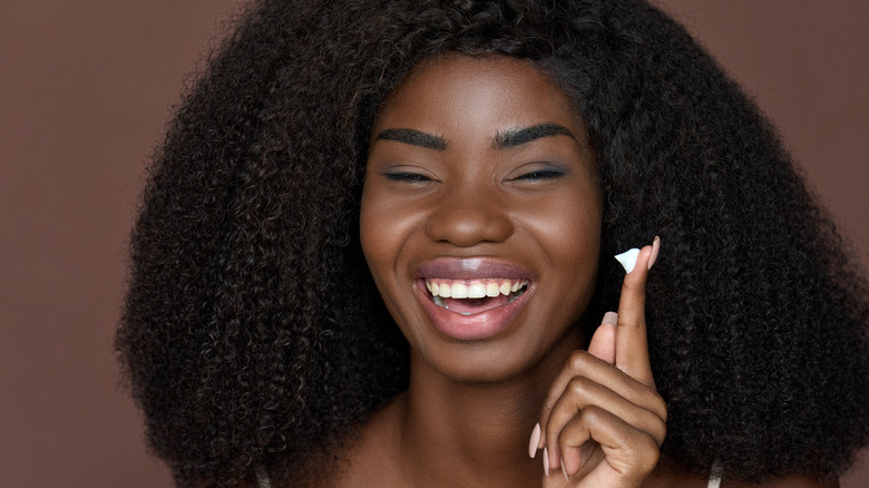 Woman smiling with cream on finger