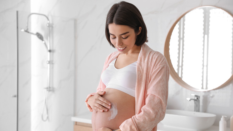 Pregnant woman applying cream