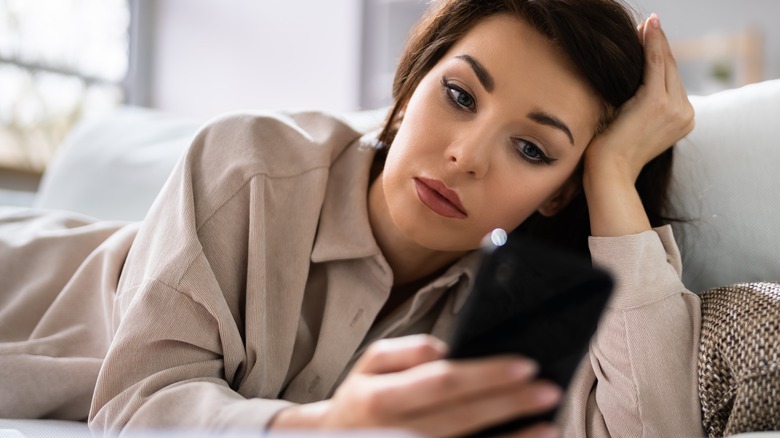 woman looking at phone on couch