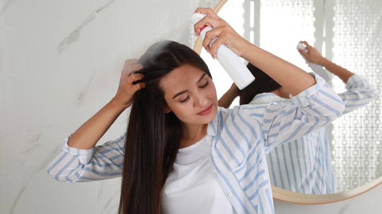 Woman applying dry shampoo to her roots