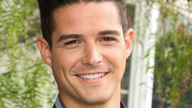 Wells Adams smiles in front of greenery backdrop