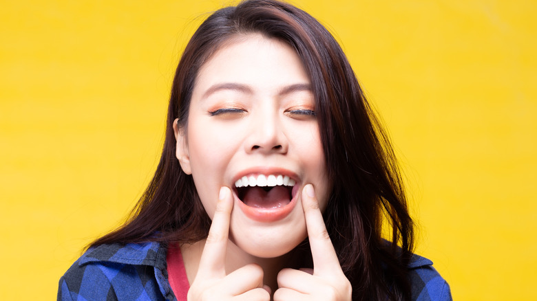 Woman smiling, pointing to teeth