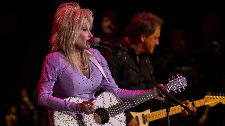 Dolly Parton singing on stage with her guitar