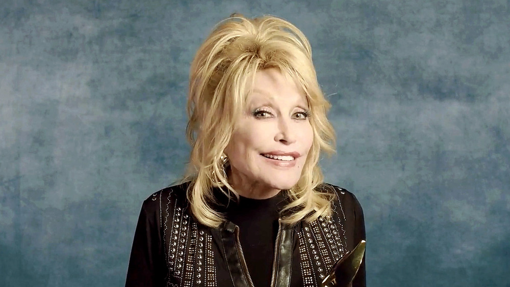 Dolly Parton posing and holding trophy