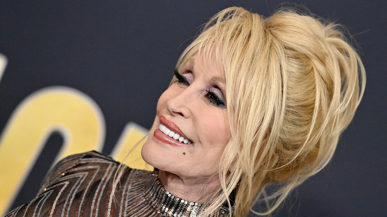 Close-up of Dolly Parton at the 2022 Country Music Awards, wearing her blonde hair in an updo with colorful eyeshow and a black and silver sequenced dress