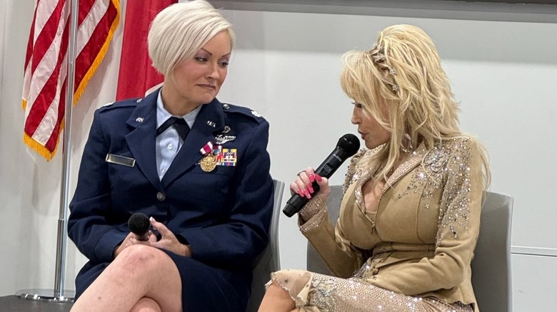 Danielle Parton and Dolly Parton sit together. Dolly speaks while Danielle, in her military dress blues, looks on lovingly.