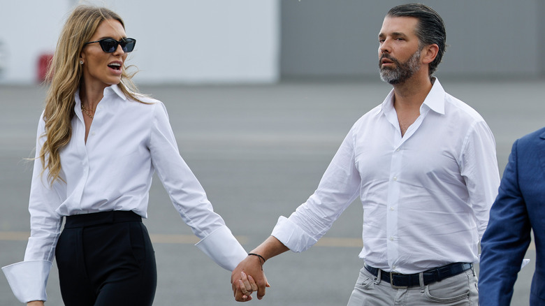 Bettina Anderson and Don Jr. walking hand in hand in matching white shirts