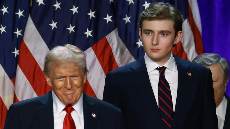 Donald and Barron Trump smiling in front of American flag