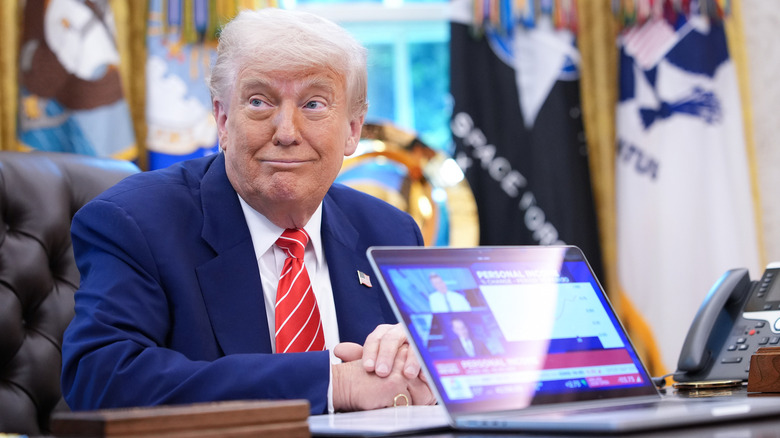 Donald Trump smirk Oval Office showing laptop