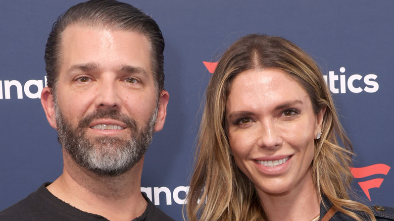 Bettina Anderson wearing a black shirt and jacket smiling next to Donald Trump Jr. who's wearing a dark shirt.