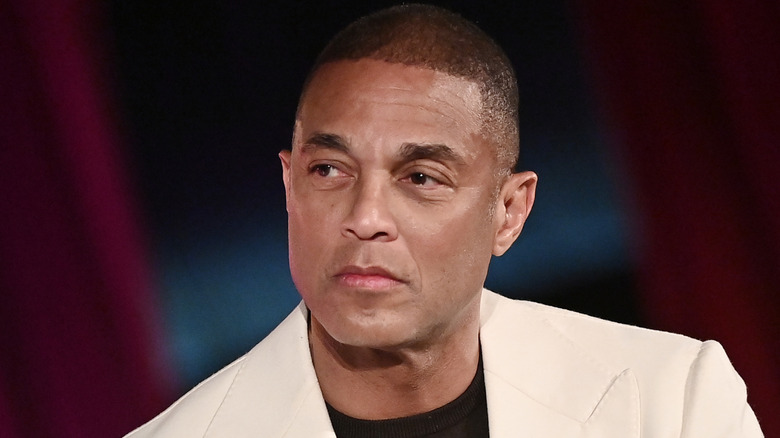 Don Lemon in a white suit jacket and black shirt against a dark background